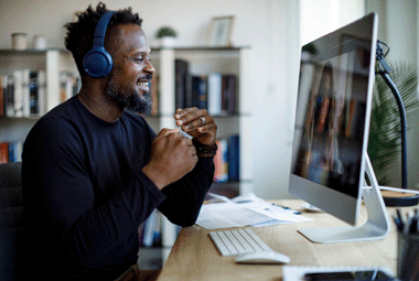 Smiling man with headphones having video call at home office