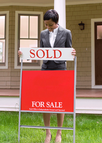 Proud real estate agent or REALTOR placing a sold sign in the yard