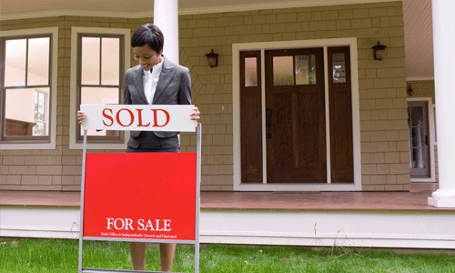 Proud real estate agent or REALTOR placing a sold sign in the yard